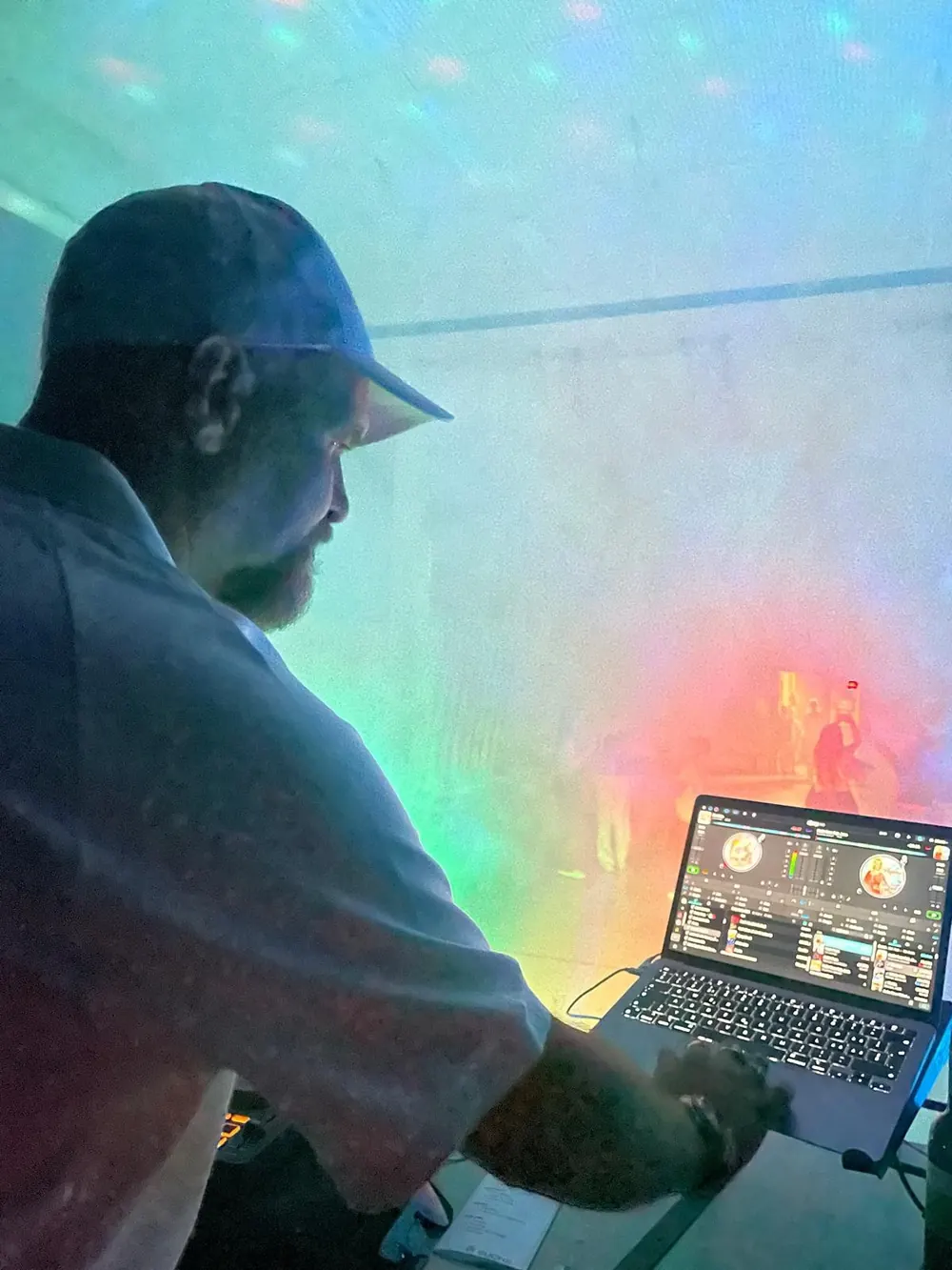 DJ am Laptop in farbigem Licht
