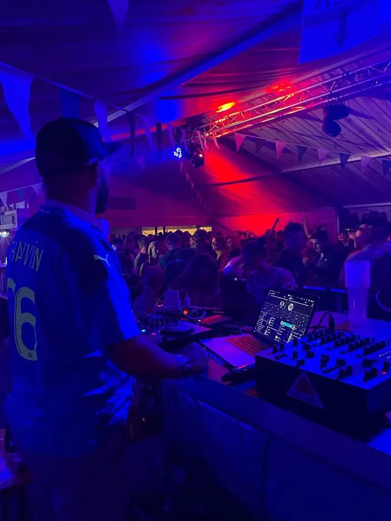 DJ von hinten vor einem vollen Zelt