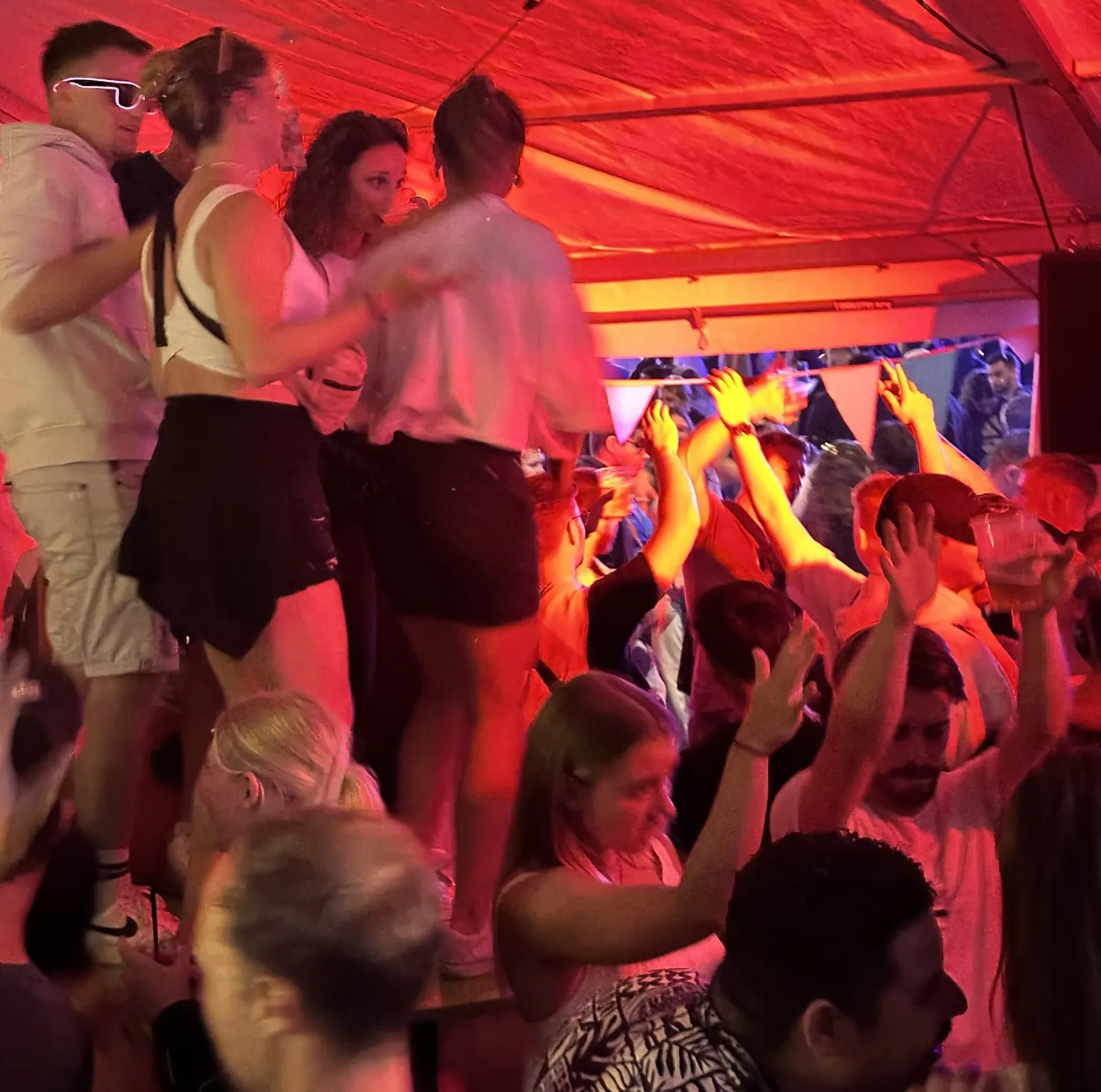 Gäste tanzen mit erhobenen Händen auf den Festbänken